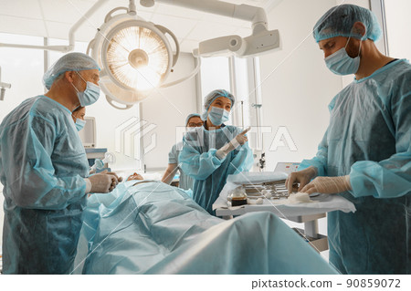 Concentrated professional surgical team working with a patient in an operation room 90859072