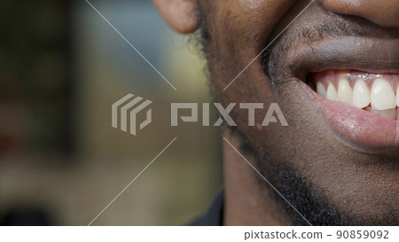 Macro shot of young man moving his lips and smiling, showing half of face on camera. Happy attractive adult with candid smile, white teeth and clean bread trim on chin. Authentic emotions. Close up. Macro shot of young man moving his lips and smiling, showing half of face on camera. Happy attractive adult with candid smile, white teeth and clean bread trim on chin. Authentic emotions. Close up. 90859092