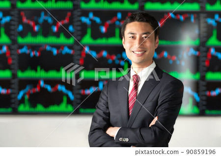 一個微笑的商人,雙臂交叉在圖表屏幕前 一個微笑的商人,雙臂交叉在圖表屏幕前 90859196