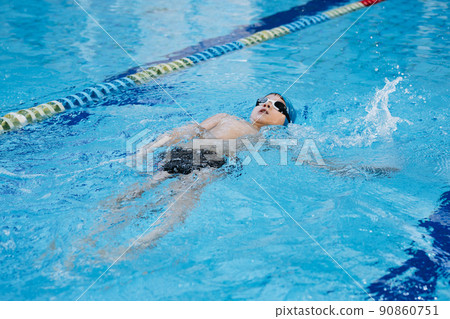 little caucasian boy wearing goggles swimming the backstroke in a pool little caucasian boy wearing goggles swimming the backstroke in a pool 90860751