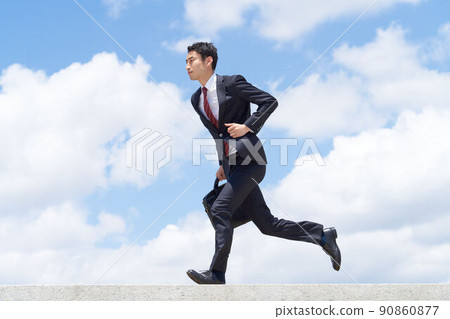 A business person who runs in a forward leaning posture under the blue sky A business person who runs in a forward leaning posture under the blue sky 90860877
