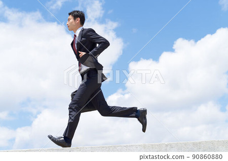 A business person in a suit running with a bag under the blue sky A business person in a suit running with a bag under the blue sky 90860880