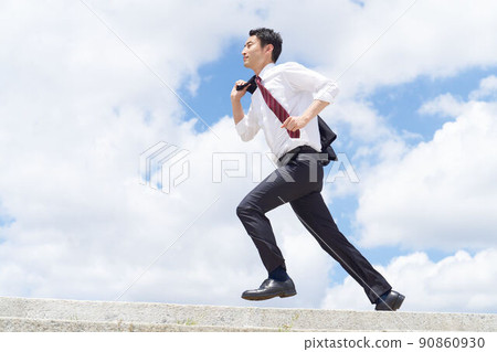 A business person running with a jacket over his shoulder under the blue sky 90860930
