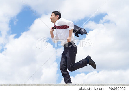 A business person running with a jacket over his shoulder under the blue sky 90860932
