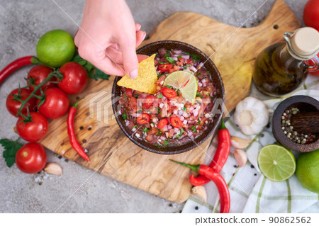 woman dips nacho chip into freshly made salsa dip sauce woman dips nacho chip into freshly made salsa dip sauce 90862562