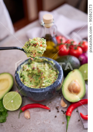 making guacamole - woman holding spoon with mixed minced ingredients making guacamole - woman holding spoon with mixed minced ingredients 90862573