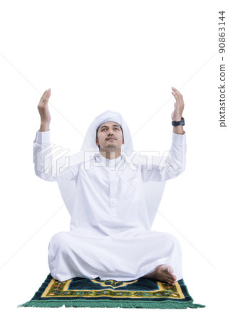 Muslim man praying while sitting on the prayer rug Muslim man praying while sitting on the prayer rug 90863144