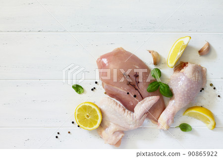 Fresh raw chicken fillets, wing, thigh and lower leg with a lemon, spices and basil on the kitchen table. Copy space. Top view. Fresh raw chicken fillets, wing, thigh and lower leg with a lemon, spices and basil on the kitchen table. Copy space. Top view. 90865922