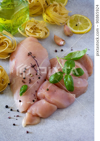 Fresh raw chicken fillet with pasta, lemon, spices and basil on the kitchen table. Food background. Fresh raw chicken fillet with pasta, lemon, spices and basil on the kitchen table. Food background. 90865924
