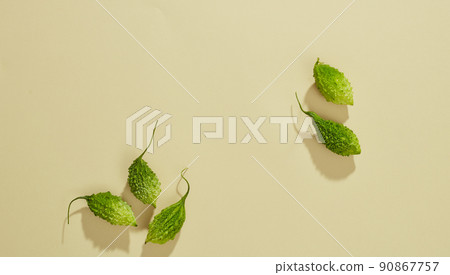 Top view of bittermelon in petri dish and green leaf with blank space colored background Top view of bittermelon in petri dish and green leaf with blank space colored background 90867757