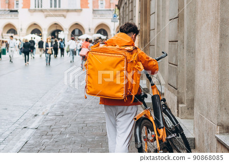 Delivery man in uniform Cycling to deliver products to customers. Driver on bike with thermal bag. No face Delivery man in uniform Cycling to deliver products to customers. Driver on bike with thermal bag. No face 90868085