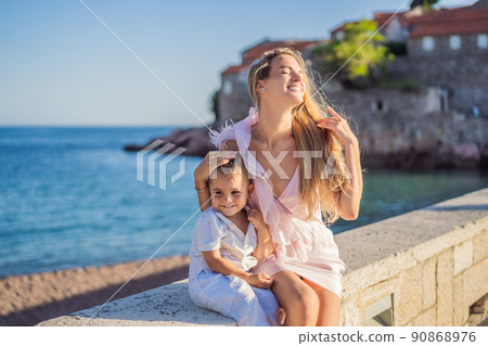 Mother and son tourists on background of beautiful view St. Stephen island, Sveti Stefan on the Budva Riviera, Budva, Montenegro. Travel to Montenegro concept Mother and son tourists on background of beautiful view St. Stephen island, Sveti Stefan on the Budva Riviera, Budva, Montenegro. Travel to Montenegro concept 90868976