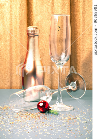 Festive golden silver Christmas New Year background with glassware. Two empty shiny wine glasses and a bottle of champagne on the table 90868981