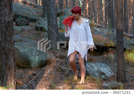 a girl with red hair and a white shirt with a rose in her hands is resting in a fabulous forest. a girl with red hair and a white shirt with a rose in her hands is resting in a fabulous forest. 90871281