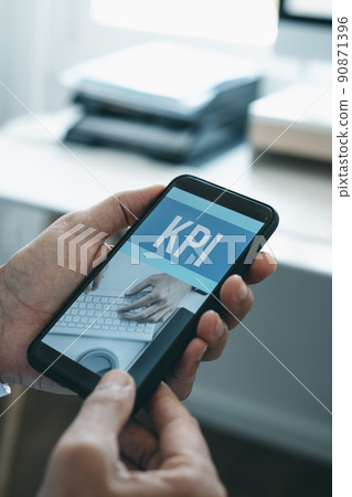 holds his smartphone that reads the text KPI 90871396