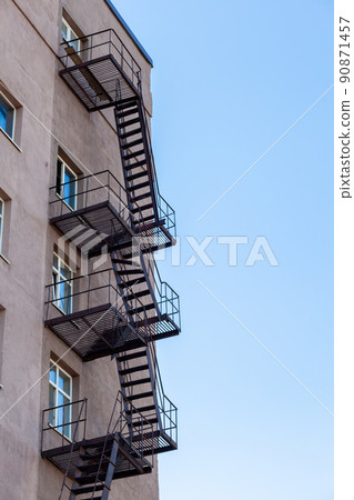 Silhouette of a fire escape on a high-rise building against a blue sky Silhouette of a fire escape on a high-rise building against a blue sky 90871457