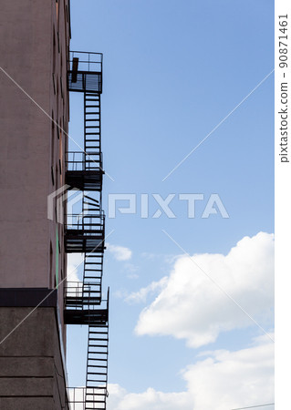Silhouette of a fire escape on a high-rise building against a blue sky 90871461