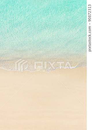 Aerial view of yellow umbrella on sandy beach. Summer and travel concept. Blue, turquoise transparent water surface of ocean, sea, lagoon. Aerial, drone view. vertical 90872313