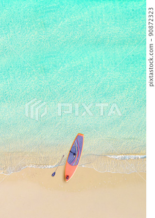 Top view of tropical Seychelles sand beach with SUP board for surfing on the shore. Blue, turquoise transparent water surface of ocean, sea, lagoon. Horizontal background. Aerial, drone view. vertical 90872323