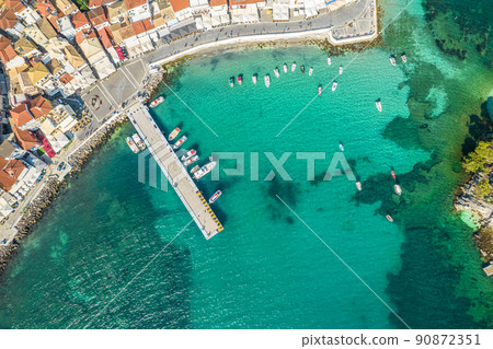 Beautiful colorful houses of seaside town, port of Parga with boats, cruise ship. Sand beach with umbrellas, tourist people, blue, turquoise sea water. Summer vacations and travel concept. Greece. 90872351