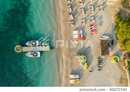 Port, pier, dock with boats, cruise ship in blue, turquoise sea water. SUP boards, rubber ring. Water sport equipment on sandy beach with sunbeds and umbrellas. Summer vacations and travel concept. Port, pier, dock with boats, cruise ship in blue, turquoise sea water. SUP boards, rubber ring. Water sport equipment on sandy beach with sunbeds and umbrellas. Summer vacations and travel concept. 90872500