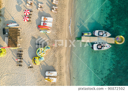 Port, pier, dock with boats, cruise ship in blue, turquoise sea water. SUP boards, rubber ring. Water sport equipment on sandy beach with sunbeds and umbrellas. Summer vacations and travel concept. Port, pier, dock with boats, cruise ship in blue, turquoise sea water. SUP boards, rubber ring. Water sport equipment on sandy beach with sunbeds and umbrellas. Summer vacations and travel concept. 90872502