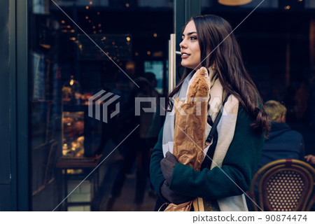 Stylish woman walking out of bakery with bread in paper bag Stylish woman walking out of bakery with bread in paper bag 90874474