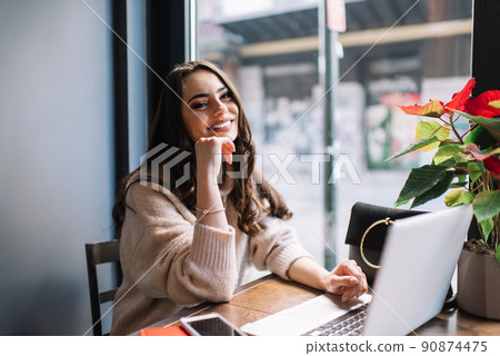 Positive woman using laptop for working in cafe at daytime Positive woman using laptop for working in cafe at daytime 90874475