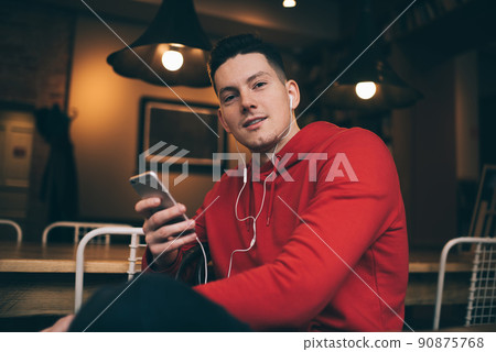 Caucasian male blogger with smartphone gadget in hand looking at camera Caucasian male blogger with smartphone gadget in hand looking at camera 90875768