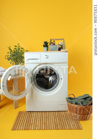 Concept of housework with washing machine on yellow background 90875831