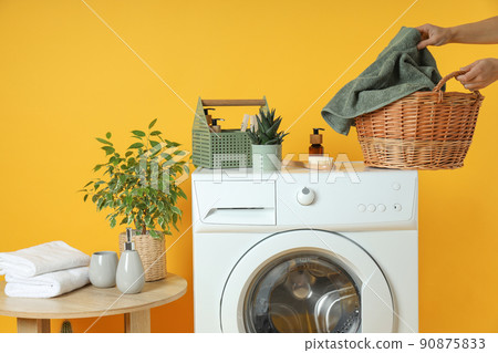 Concept of housework with washing machine on yellow background Concept of housework with washing machine on yellow background 90875833