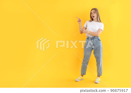 Young attractive girl in jeans on yellow background Young attractive girl in jeans on yellow background 90875917