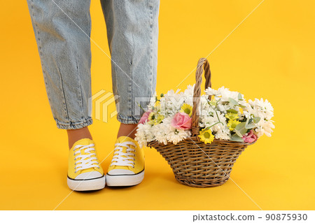 Girl legs and basket of flowers on yellow background Girl legs and basket of flowers on yellow background 90875930