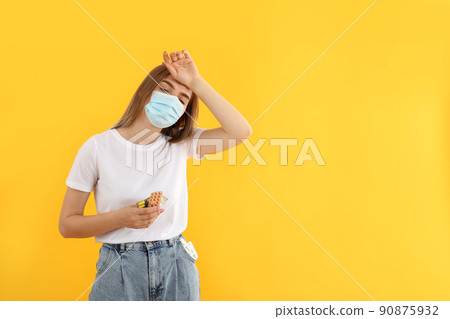 Sick girl in mask with pills on yellow background Sick girl in mask with pills on yellow background 90875932