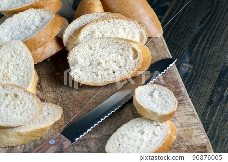 wheat baguette cut into pieces on a cutting board wheat baguette cut into pieces on a cutting board 90876005