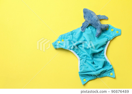 Concept of baby clothes with reusable diapers on yellow background Concept of baby clothes with reusable diapers on yellow background 90876489