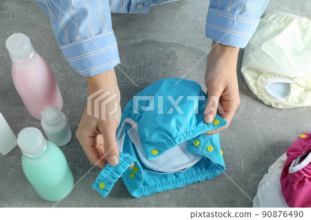 Concept of baby clothes with reusable diapers on gray textured background 90876490