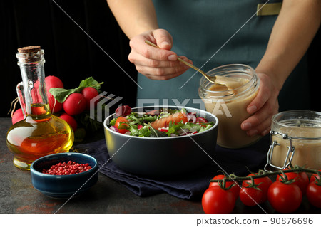 Concept of cooking vegetable salad with tahini sauce on dark textured table Concept of cooking vegetable salad with tahini sauce on dark textured table 90876696