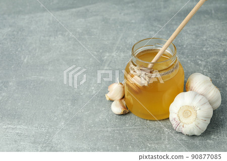 Concept of treatment colds with honey and garlic on gray textured background Concept of treatment colds with honey and garlic on gray textured background 90877085