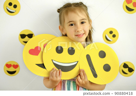 Cute smiling girl with emoticons in her hands with a variety of emotional states. Cute smiling girl with emoticons in her hands with a variety of emotional states. 90880418