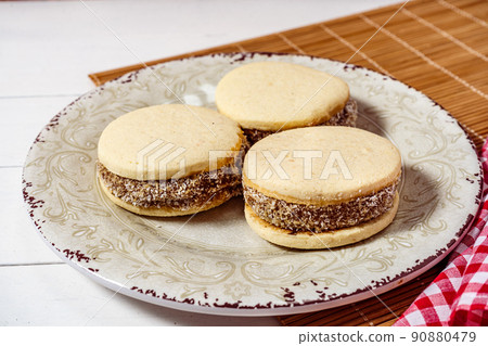 Classic Argentinean cornstarch and dulce de leche alfajores with coconut on a vintage plate. high view. sweet snack Classic Argentinean cornstarch and dulce de leche alfajores with coconut on a vintage plate. high view. sweet snack 90880479