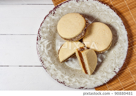 Classic Argentinean cornstarch and dulce de leche alfajores with coconut on a vintage plate. Top view. Copy text. sweet snack Classic Argentinean cornstarch and dulce de leche alfajores with coconut on a vintage plate. Top view. Copy text. sweet snack 90880481