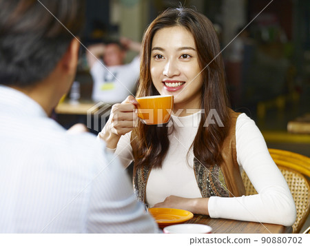 young asian couple lovers sitting at table chatting talking face to face in coffee shop 90880702