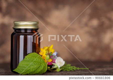 Bottle with vitamin tablets and fresh flowers herbalized on natural wooden background. Transparent medicine bottle of brown glass mockup. Copy space. Bottle with vitamin tablets and fresh flowers herbalized on natural wooden background. Transparent medicine bottle of brown glass mockup. Copy space. 90881806