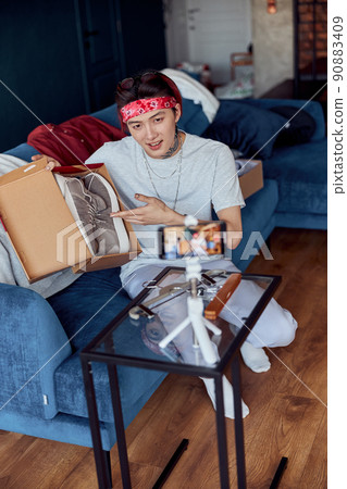 Smiling Asian guy making video online while using smartphone on tripod Smiling Asian guy making video online while using smartphone on tripod 90883409