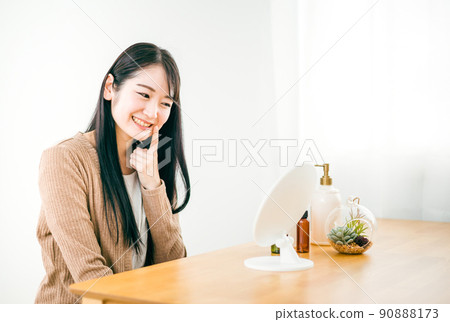 A woman who looks in the mirror in the room and has healed her rough skin (smile, nasolabial fold) A woman who looks in the mirror in the room and has healed her rough skin (smile, nasolabial fold) 90888173