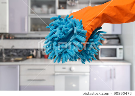 Woman's hand in a protective glove with a rag at the kitchen. 90890473