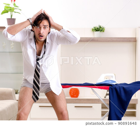 Young man ironing in the bedroom Young man ironing in the bedroom 90891648