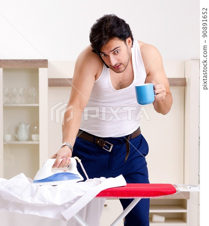 Young man ironing in the bedroom 90891652