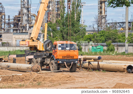 Construction work on pipe laying of pipeline into trench using a crane Construction work on pipe laying of pipeline into trench using a crane 90892645